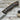 A hunting knife with a walnut handle and a stainless steel blade, accompanied by a brown leather sheath, placed on a wooden surface.